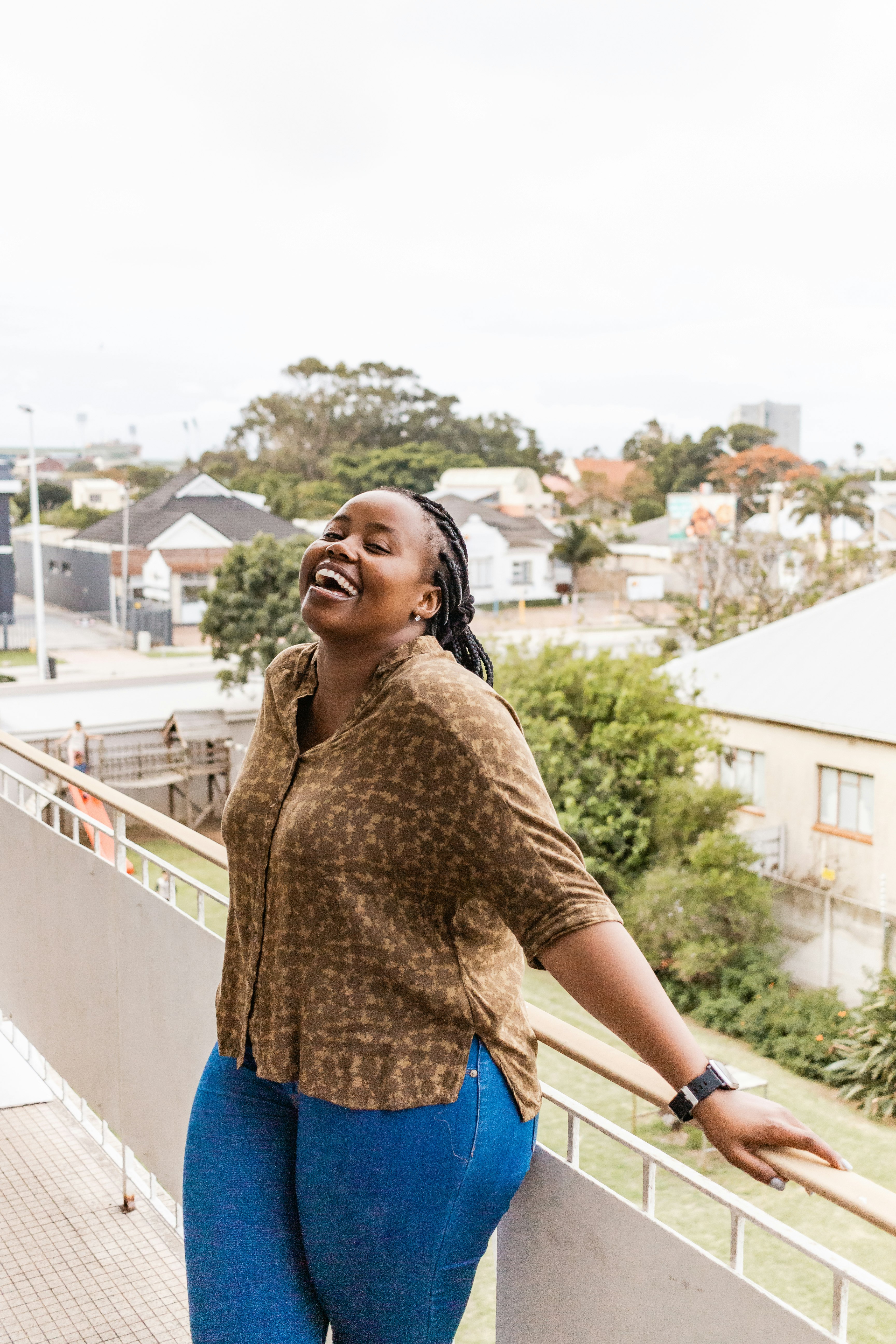 woman in brown long sleeve shirt and blue denim shorts standing on balcony during daytime